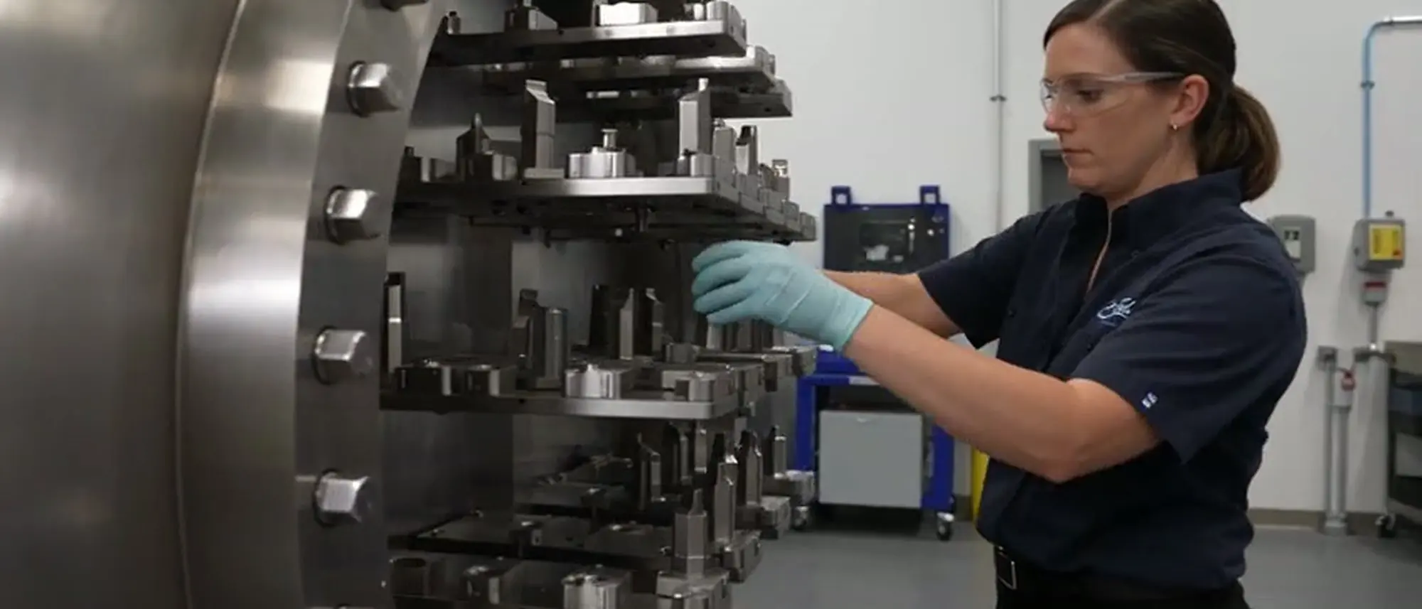 A SurfTech operator loading components onto a fixture rack at the open door of the coating chamber