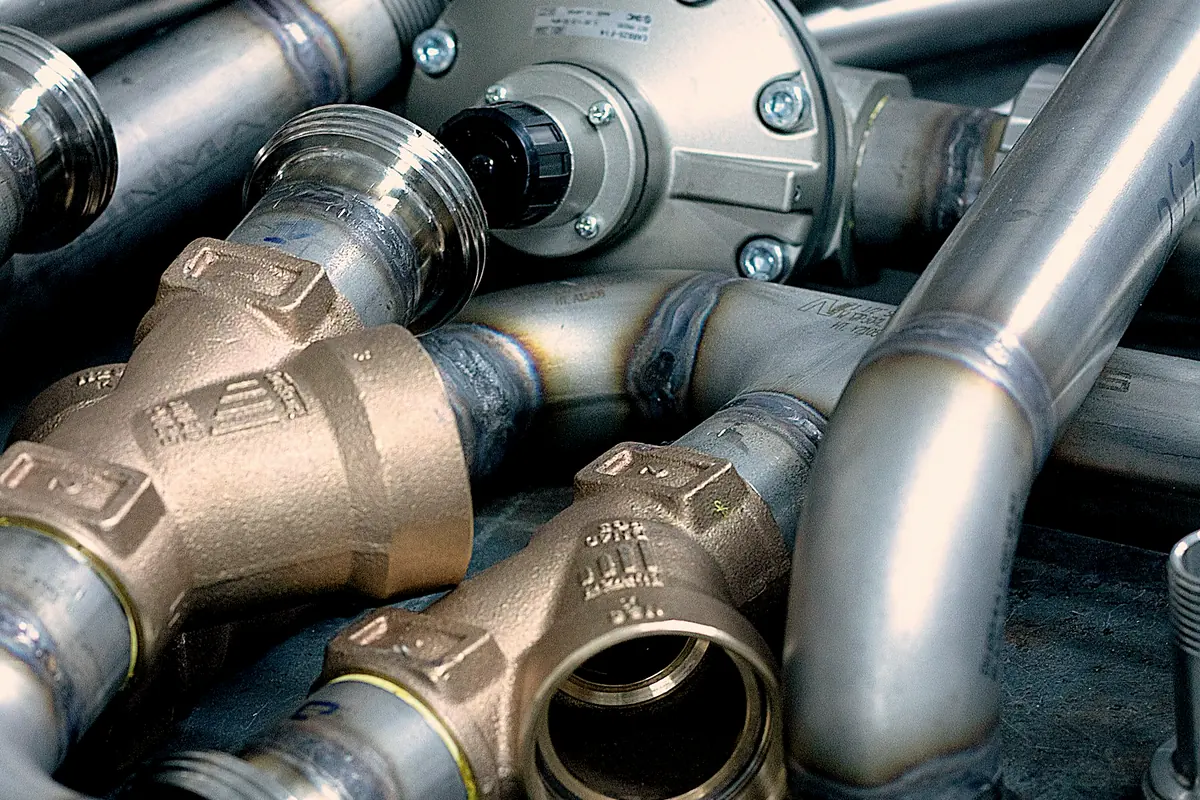 Stainless pipe elbows and threaded brass valve bodies on a workbench