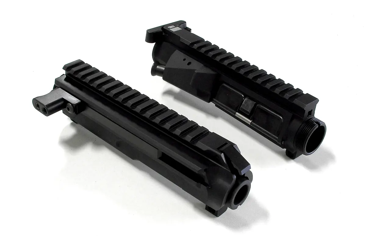 Two machined aluminum rifle upper receivers on a white studio background