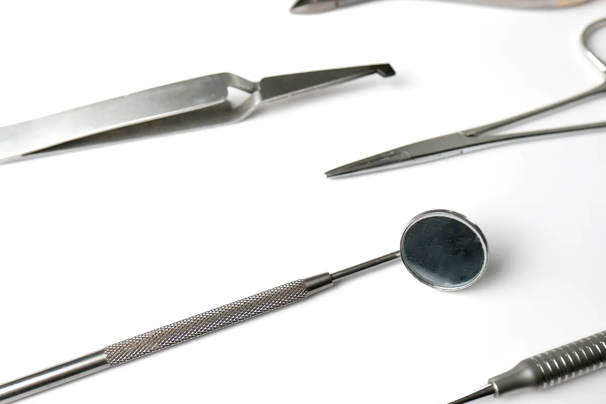 Stainless surgical and dental instruments laid out on a bright white surface