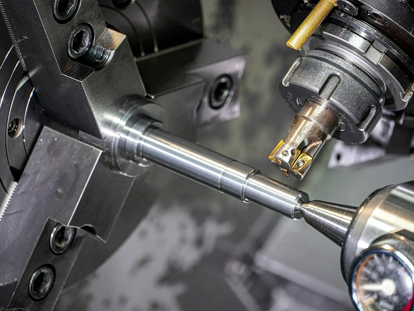 A steel rod turning in a lathe chuck under an indexable carbide cutting tool