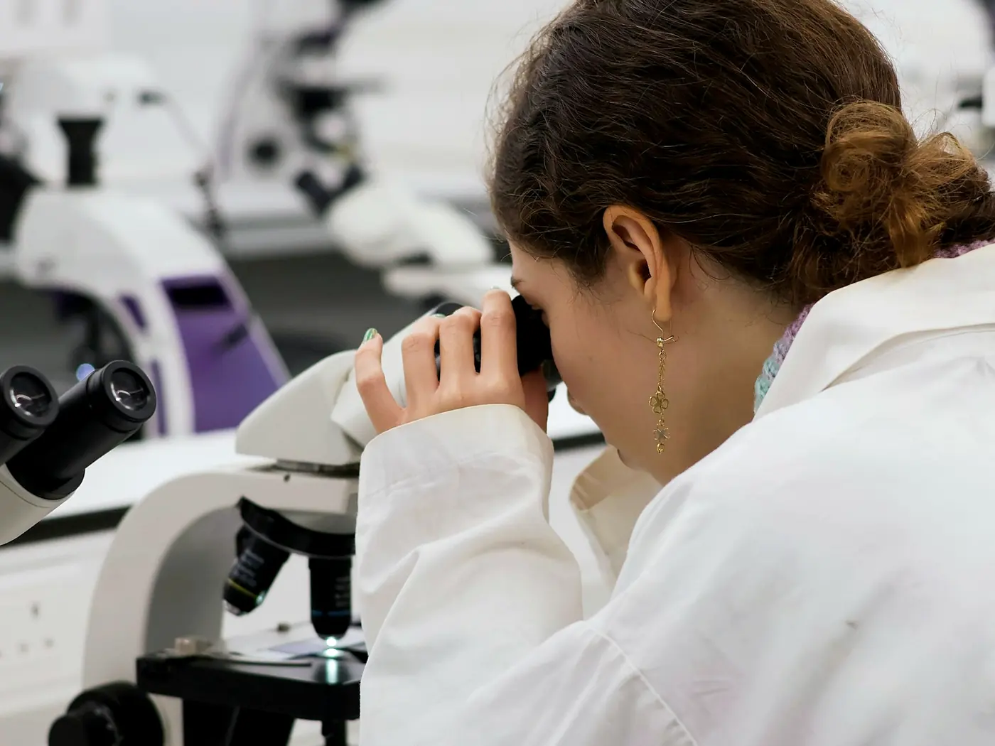 A technician looking through a microscope at a laboratory bench